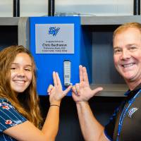 Two guests using the "Laker for a Lifetime" gesture to point at a named locker at the Jamie Hosford Football Center dedication.